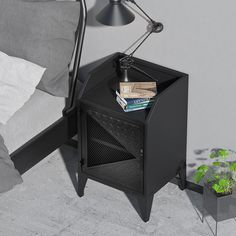 a night stand with books on it next to a plant and a bed in the background