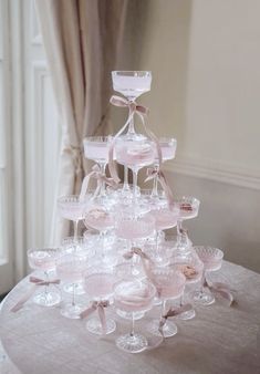 a table topped with lots of wine glasses on top of a white table cloth covered table