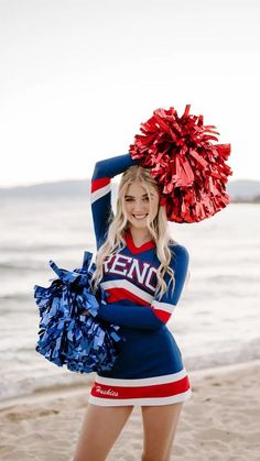 a cheerleader posing on the beach with her pom - poms