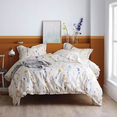 a bed with white and yellow comforters in a bedroom next to a large window