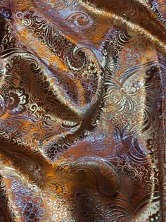 an orange and brown paisley print fabric with metallic foil on the bottom, it is very shiny