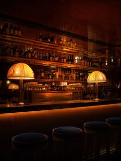 a dimly lit bar with stools and lamps