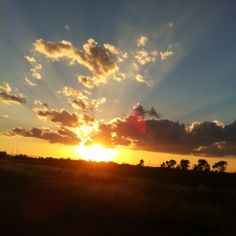 the sun is setting over an open field