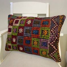 a white chair with a multicolored pillow on it's back and side