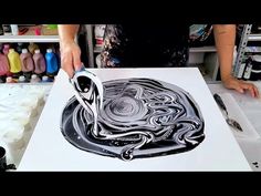 a person is using a large knife to paint an abstract design on a white paper