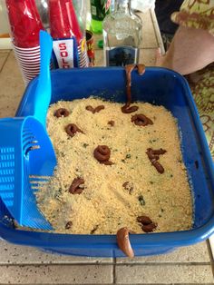 a large blue dish filled with food on top of a counter next to soda bottles