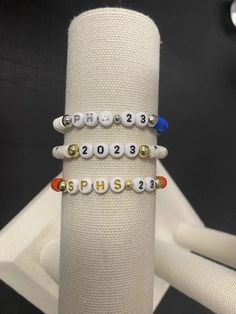 "Design the personalized heishi bracelet for your 2023 graduating senior! Choose from one color or multiple PLUS sterling silver or 14K gold filled beads. These heishi bead bracelets are double strung with thick elastic string for durability.  Heishi clay beads = 1x6mm Plastic letter beads = 4x7mm Metal beads = 6mm & 4mm ** NUMBER BEADS ONLY AVAILABLE IN WHITE & BLACK AS SHOWN ** EXAMPLES OF HOW TO EXPLAIN IF YOU WANT A HEART BEAD ON YOUR BRACELET: SPHS (red heart) 23 SPHS (gold heart) 23 SPHS ( Senior Friendship Bracelets, Senior Year Bracelets, Class Of 2024 Bracelets, Senior Bracelets Ideas, Senior Bracelets, Graduation Bracelet Ideas, Senior Diy, Senior Era, Senior Graduation Gifts