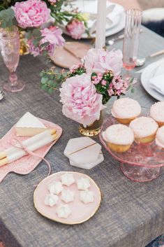 a table topped with pink and white cupcakes next to plates filled with cake