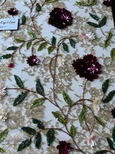 an embroidered fabric with flowers and leaves on it