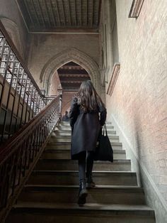 a woman is walking down some stairs with her hand on her shoulder and carrying a bag