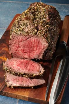 a large piece of meat sitting on top of a cutting board next to a knife