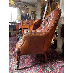 a brown leather chair sitting on top of a rug next to a wooden desk and mirror