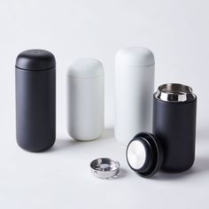 three black and white containers sitting next to each other on top of a white surface