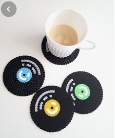 three coasters with smiley faces on them next to a cup of coffee