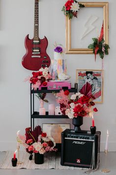 a guitar, flowers and candles are sitting on a shelf