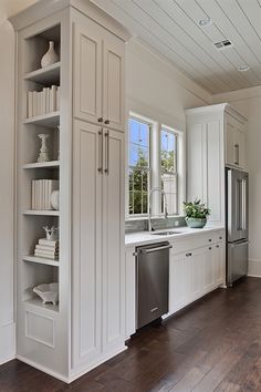 a kitchen with white cabinets and wood floors