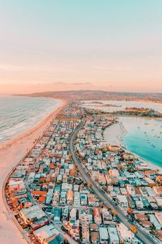 an aerial view of a city by the beach with boats in the water and sand