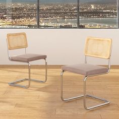 two chairs sitting on top of a hard wood floor next to a window with city lights in the background