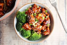 a bowl filled with chicken and broccoli covered in sesame seeds