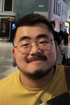 a man with glasses and a mustache is taking a selfie in the street at night