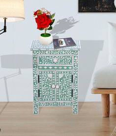 a white and green cabinet with a red rose on top in a living room setting