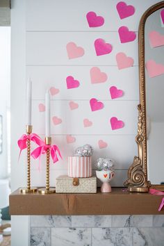 a mantle with candles and decorations on it in front of a wall decorated with hearts