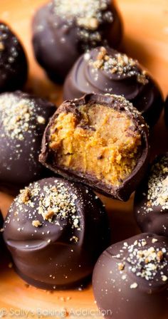 chocolate covered candies with gold sprinkles on wooden cutting board, closeup