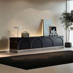 a living room with a large black cabinet and potted plant on the sideboard