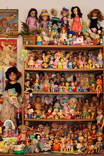 there are many dolls on the shelves in this room