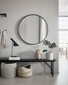 a black and white room with a round mirror on the wall next to a bench