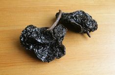 two black raisins sitting on top of a wooden table