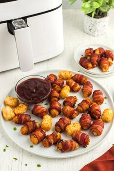 bacon wrapped chicken bites with ketchup on a plate next to an air fryer