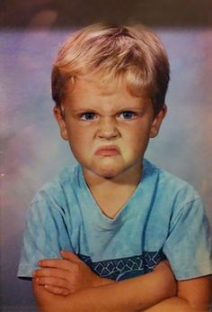 an old photo of a young boy with blue eyes and blonde hair, wearing a blue shirt