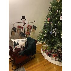 a christmas tree with presents in it next to a sleigh on the floor