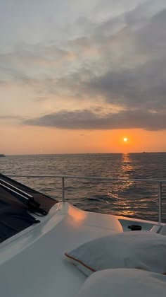 the sun is setting over the ocean on a boat