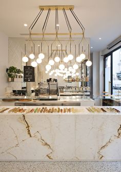 a marble counter in a restaurant with lights hanging from the ceiling