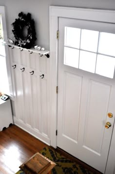 a white door with some hooks on the side and a table in front of it