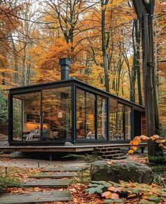 a small glass cabin in the woods surrounded by fall foliage and trees with yellow leaves