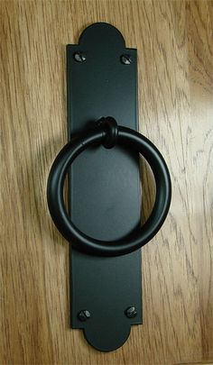 a black door handle on top of a wooden table with a metal ring in the center