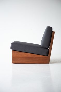 a chair that is sitting up against a white wall with a black cushion on it