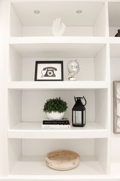 a white shelf filled with books and other items on top of eachother in a room