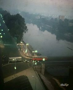 a view of a river and bridge at night from a train station in the rain