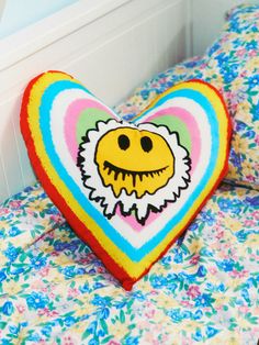 a heart shaped pillow sitting on top of a bed next to pillows with an image of a smiling face