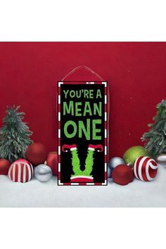 there is a sign that says you're a mean one on the wall next to christmas ornaments