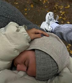 a person is sleeping on the ground with their head wrapped in a blanket and shoes