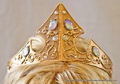 a woman wearing a gold tiara with opal stones on it's head