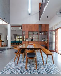 the dining room table is surrounded by wooden shelves and blue patterned rugs on the floor