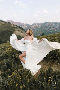 a woman in a white dress is posing on a hill