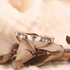 a wedding band with green and white stones on top of it sitting on a flower