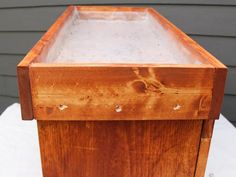 a wooden box sitting on top of a white cloth covered table next to a house